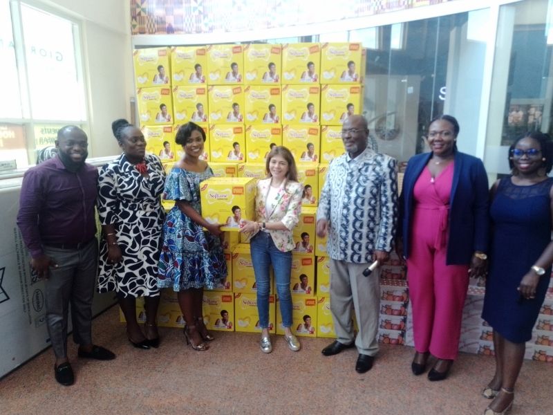 Nana Adutwumoah receiving a carton of sanitary pads from the Director of Melcom Group of Companies. With them are Mr Avenorgbo (3rd right) and staff from Guinness Ghana Breweries PLC