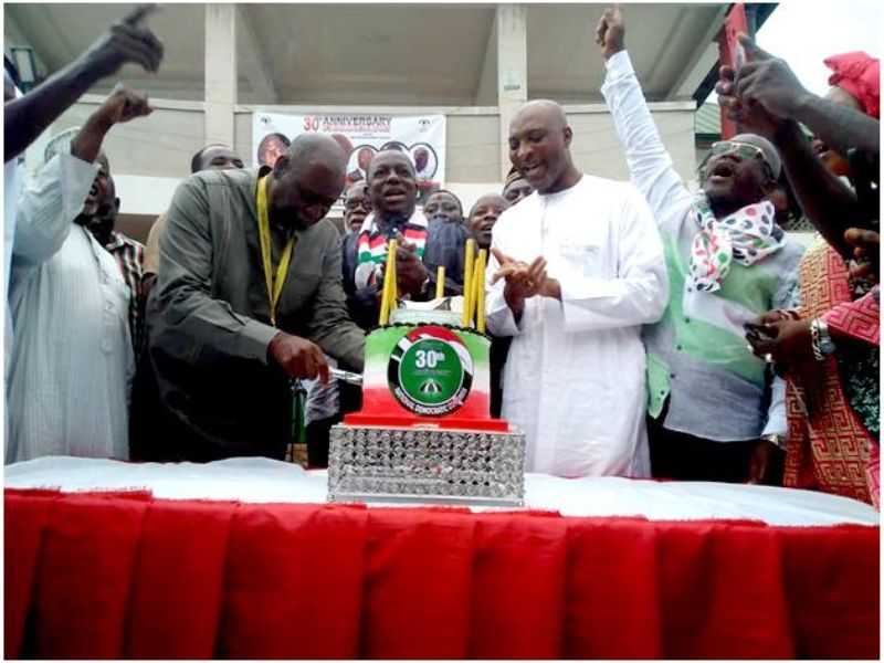 Dr Samuel Sarpong, former Ashanti Regional Minister, cutting the Anniversary Cake, while MP Mubarak, others look on admiringly