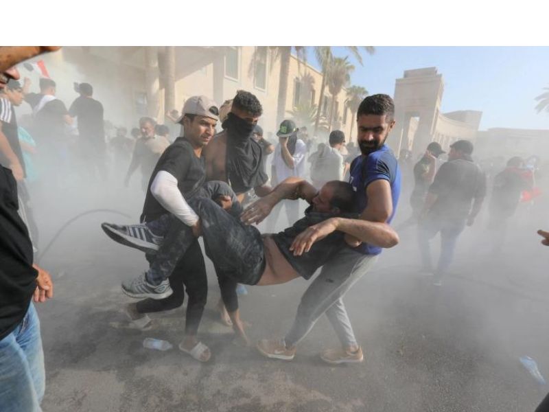 Supporters of Iraqi Shia cleric Muqtada al-Sadr help injured protestors during clashes with anti-riot forces.