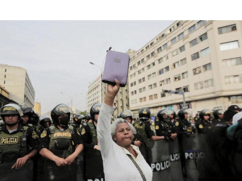 A demonstrator holds up a Bible in front of police officers during demonstrations demanding new presidential elections after the removal of Castillo