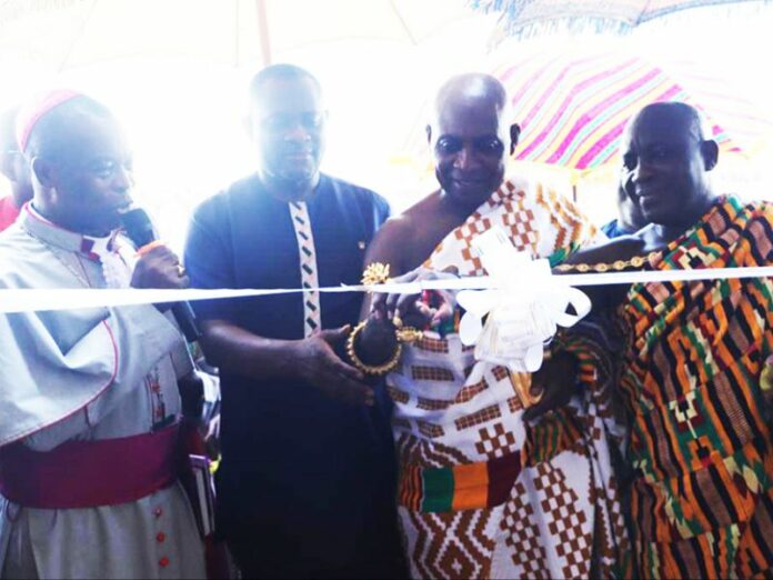 Domeabrahene Nana Kusi being assisted by Otumfuo's Hiahene and the Methodist Bishop of Kumasi to cut the tape to commission the block