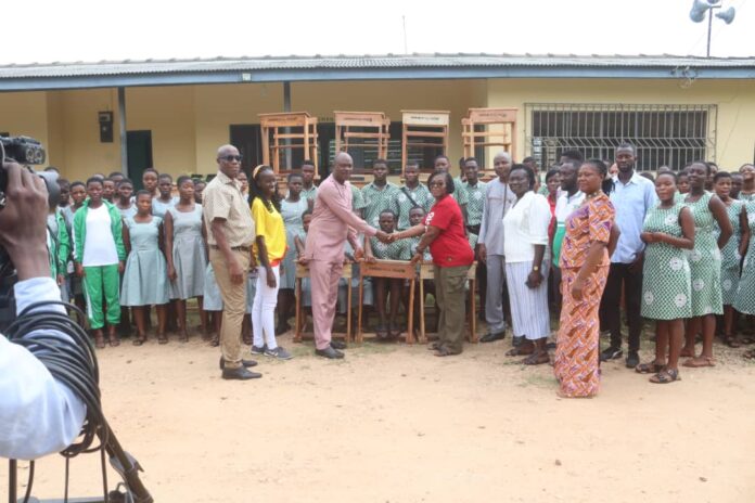Rev Ackwerh in a handshake with Mrs Ocloo at the presentation of the mono desks. With them are some staff, PTA Executives and students of ASTEC