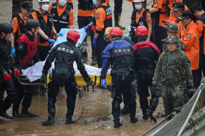 Rescue workers carry the body of a victim recovered near a submerged underpass in Cheongju, South Korea
