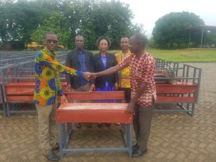 The Akatsi-North DCE, Mr Simon Peter Kofi Ofosu (left) presenting the dual desks to the District Director of Education, Mr Dominic Dzanado