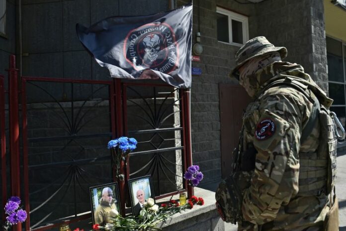 A Wagner fighter stands in front of a makeshift memorial with portraits of Russian mercenary chief Yevgeny Prigozhin and Wagner Group commander Dmitry Utkin in Novosibirsk, Russia