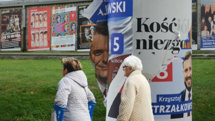 A defaced poster for a PiS candidate billows in the wind in Warsaw. Poland's election campaign has been toxic, with polls indicating a tight result.