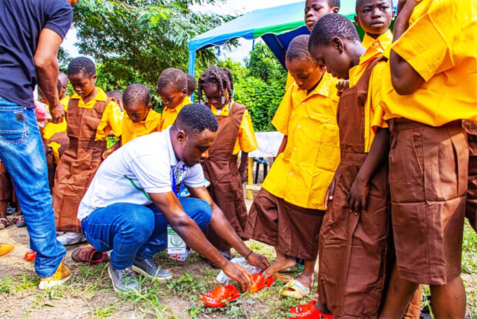 The CEO of As I Grow assisting some of the children to put on their footwear and uniforms after the donation