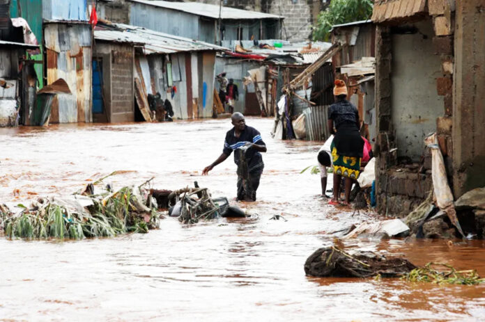 Mathare residents wade through floodwaters as they recover their belongings after the Nairobi river burst its banks