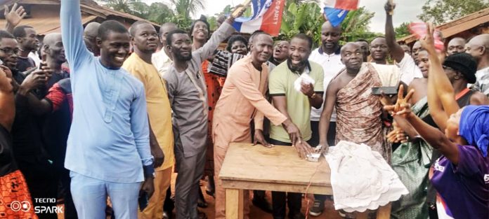 The DCE (left) MP (middle) and Nana Akoto, Grumesa Odikro (right) jointly switch on the light to commission the project