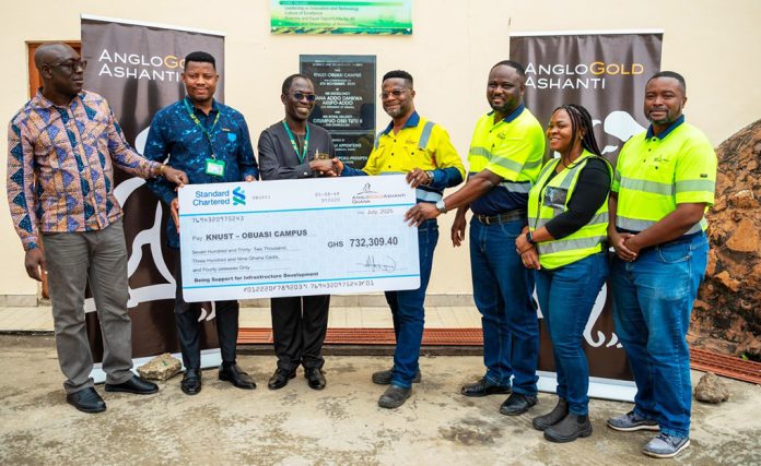 Mershack Baah (right) in a hand shake with Prof. Darkwah (left) while handing over a dummy cheque to the University