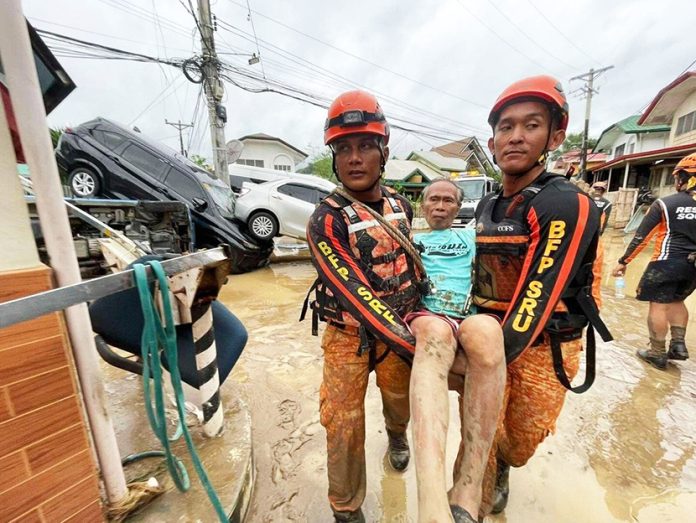 Rescue workers walk carrying a man after flooding caused by Typhoon Kalmaegi