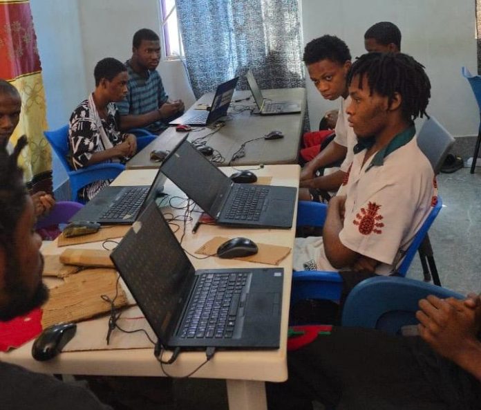 The suspects seated behind their computers at their hideout in Pokuase following their arrest.