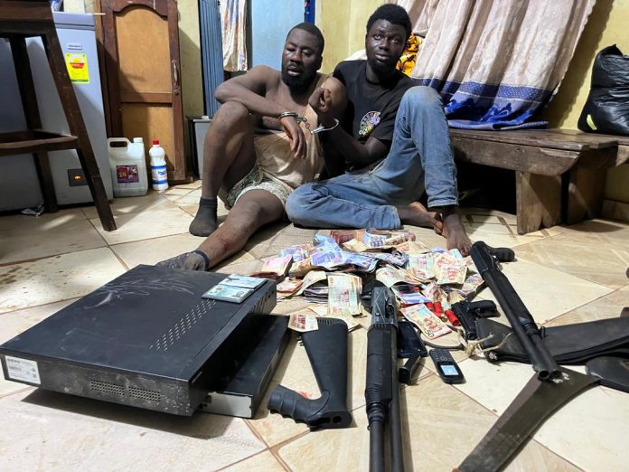 Two of the suspects with the exhibits allegedly found on them displayed in front of them.