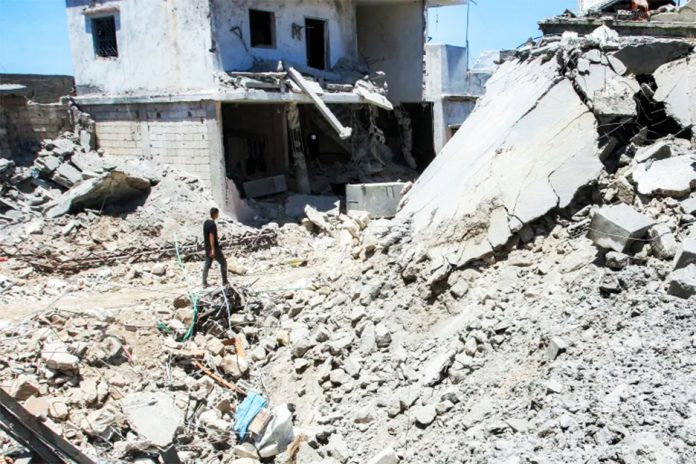 A man walks past the rubble of a destroyed building in the village of Deir Qanoun en-Nahr in southern Lebanon