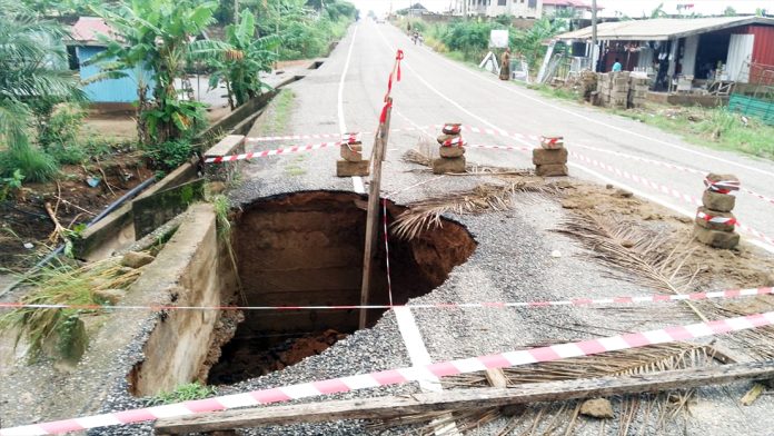 The damaged section of the road which has negative impact on the bridge.