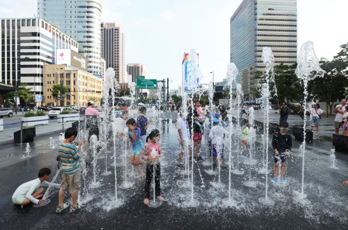 Children play in the water fountains during a heatwave