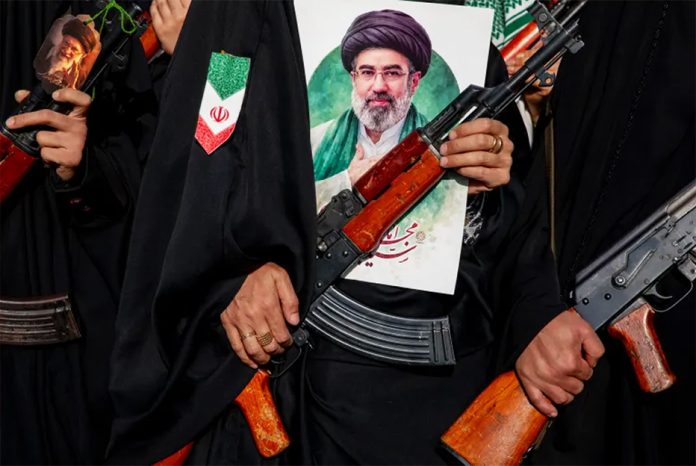 Women carry rifles and hold a picture of new Supreme Leader Mojtaba Khamenei